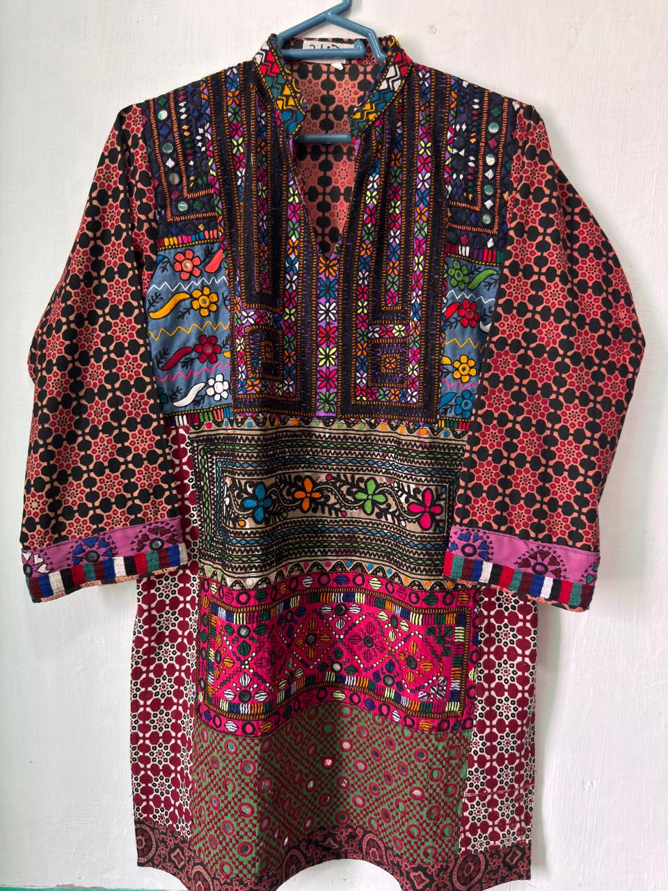 Green hand-embroidered kurta hanging against a pale background